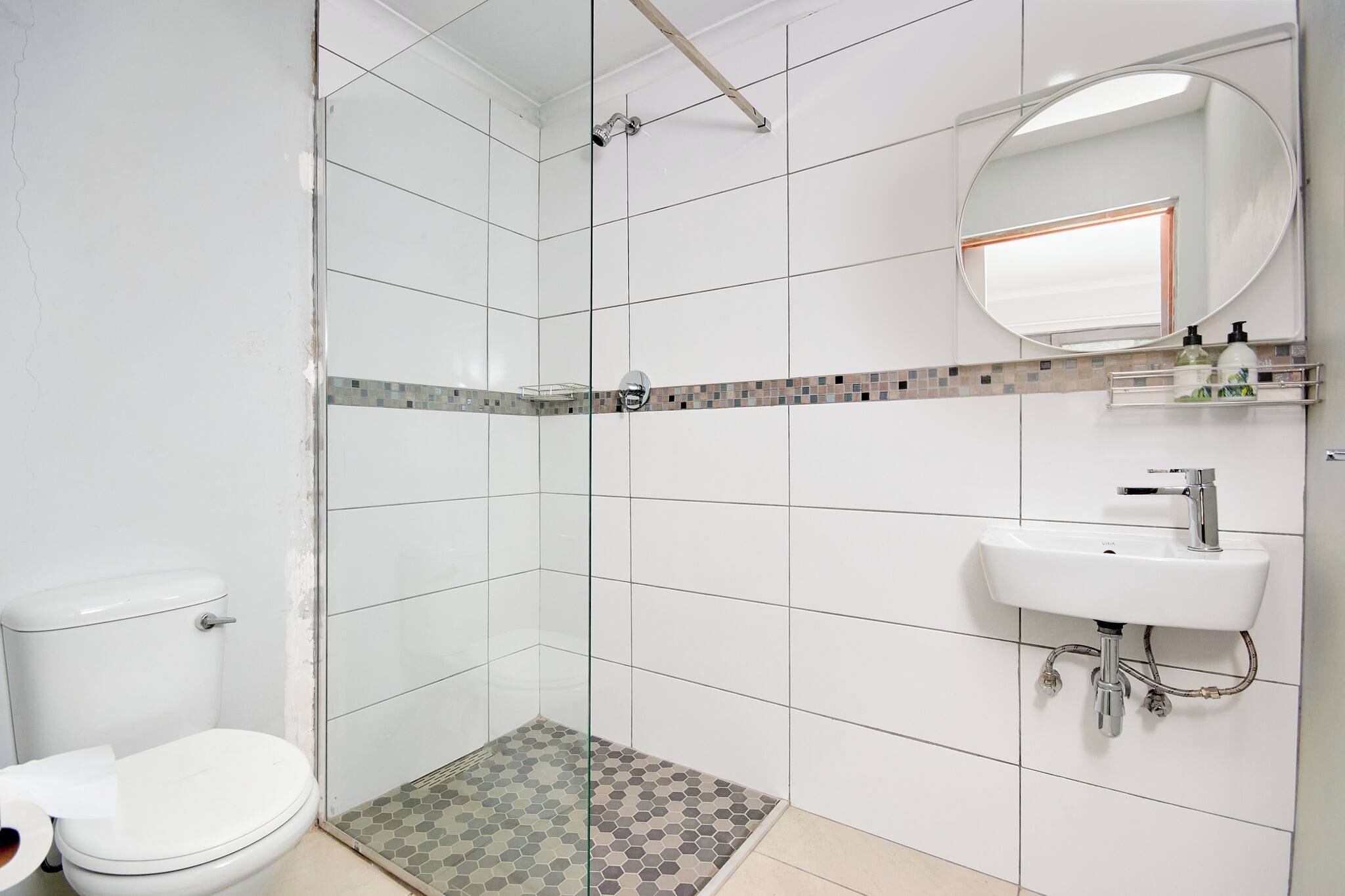 A bathroom with a toilet, shower, and sink.