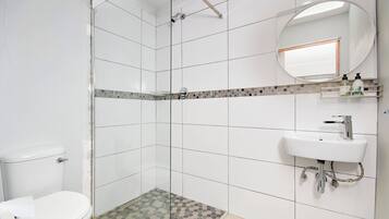 A bathroom with a toilet, shower, and sink.