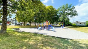 A playground with slides and climbing structures, surrounded by grass and trees. - Homely 1BR in Central Vancouver | 5mins walk to skytrain, 10 mins to DT (Vancouver)