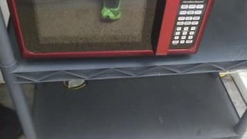 A red microwave oven on a black shelf.