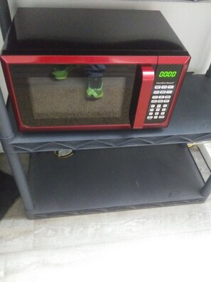 A red microwave oven on a black shelf. - 1 Bed 1 Bath Efficiency unit (North Platte)