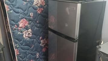 A compact kitchenette with a refrigerator and microwave.