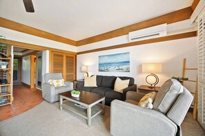 A living room with a sofa, armchairs, a coffee table, and a painting on the wall. - Aloha Sunrise | AC | POOL | HOT TUB (Koloa)
