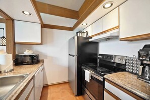 A modern kitchen with a built-in oven, a refrigerator, and a coffee machine. - Aloha Sunrise | AC | POOL | HOT TUB (Koloa)