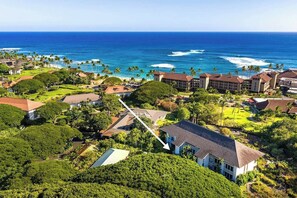 A coastal resort with multiple buildings, a clear view of the ocean, and lush greenery. - Aloha Sunrise | AC | POOL | HOT TUB (Koloa)
