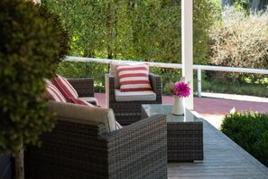 A wicker outdoor seating area with cushions and a vase of flowers. - Charming 1-Bed Cottage in Historic Berrima (Berrima)