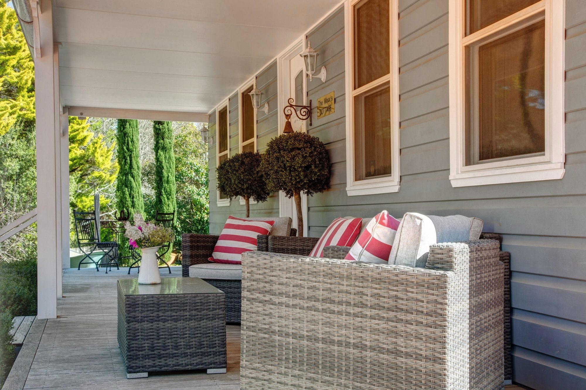 A covered porch with wicker furniture, a table, and a hanging planter.