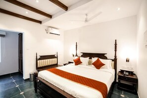 Ein Hotelzimmer mit einem großen Bett, einem hölzernen Kopfteil, einem Nachttisch und einem Deckenventilator.