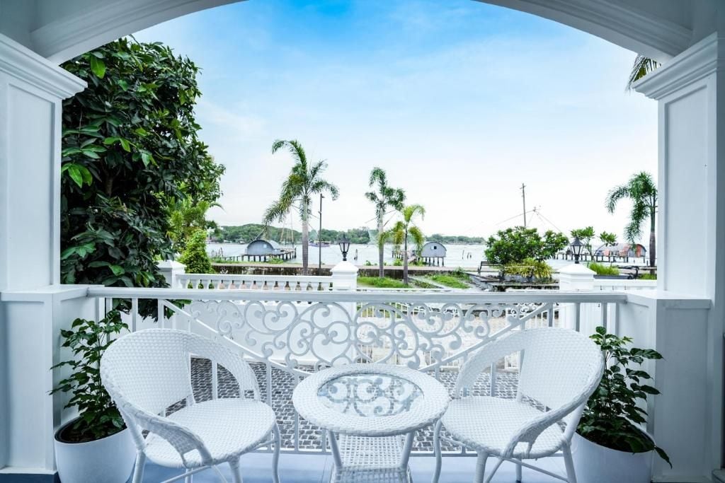 A balcony with white wicker furniture and potted plants.