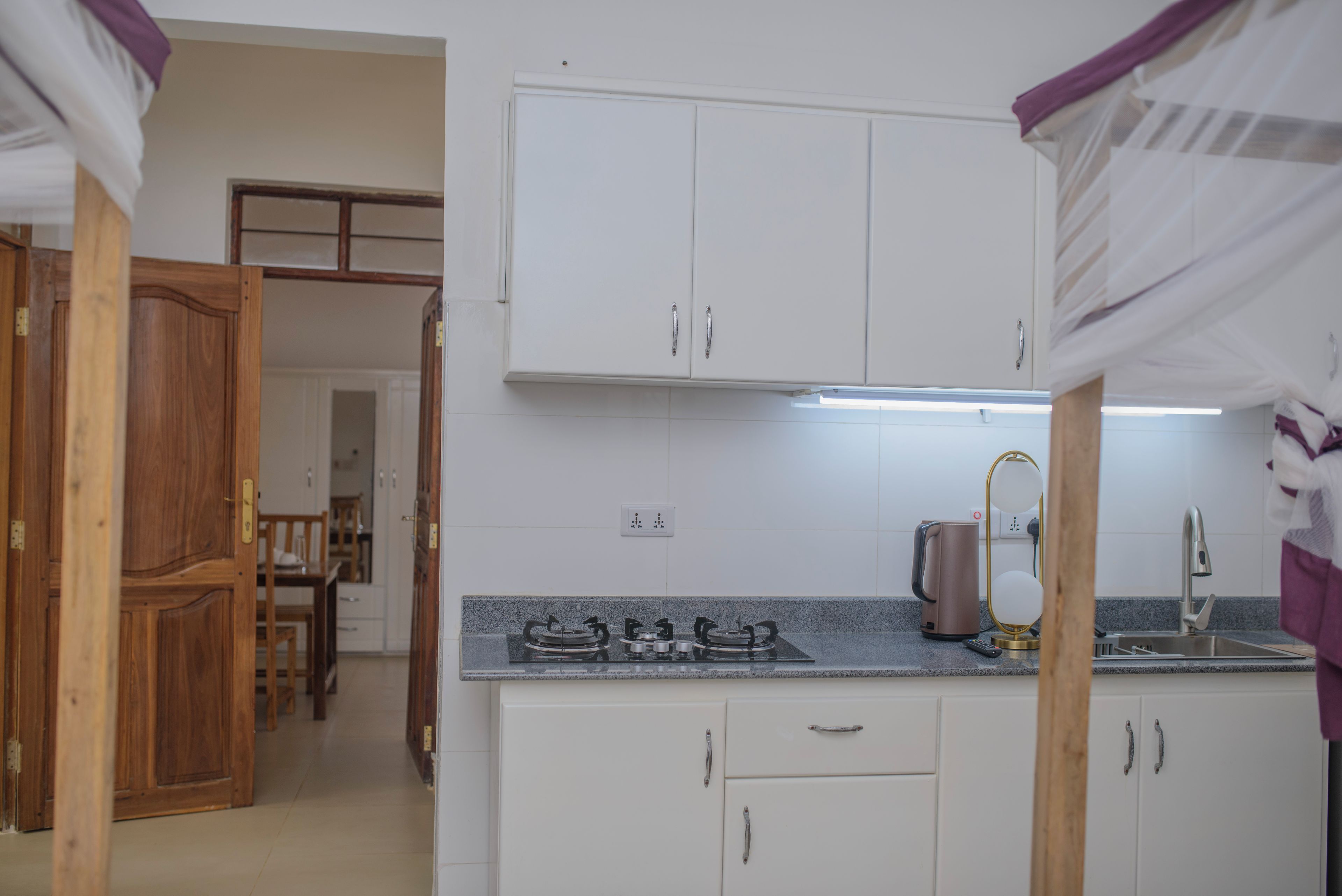 Una cocina compacta con armarios blancos, cocina a gas y cafetera.