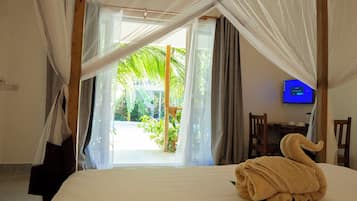 Een hotelkamer met een bed, een televisie en uitzicht op een tuin.