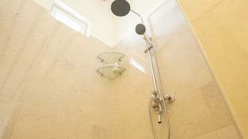 A shower with a glass-enclosed glass door, a handheld showerhead, and a wall-mounted faucet.