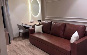 A modern room with a brown leather sofa, a desk, and a chair. - Luxury Studio Apartment Khar West | Fully Furnished Mumbai Stay (Mumbai)