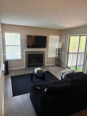 A living room with a fireplace, a flat-screen TV, and a large window. - Modern cozy 1bedroom in Union City! (Union City)