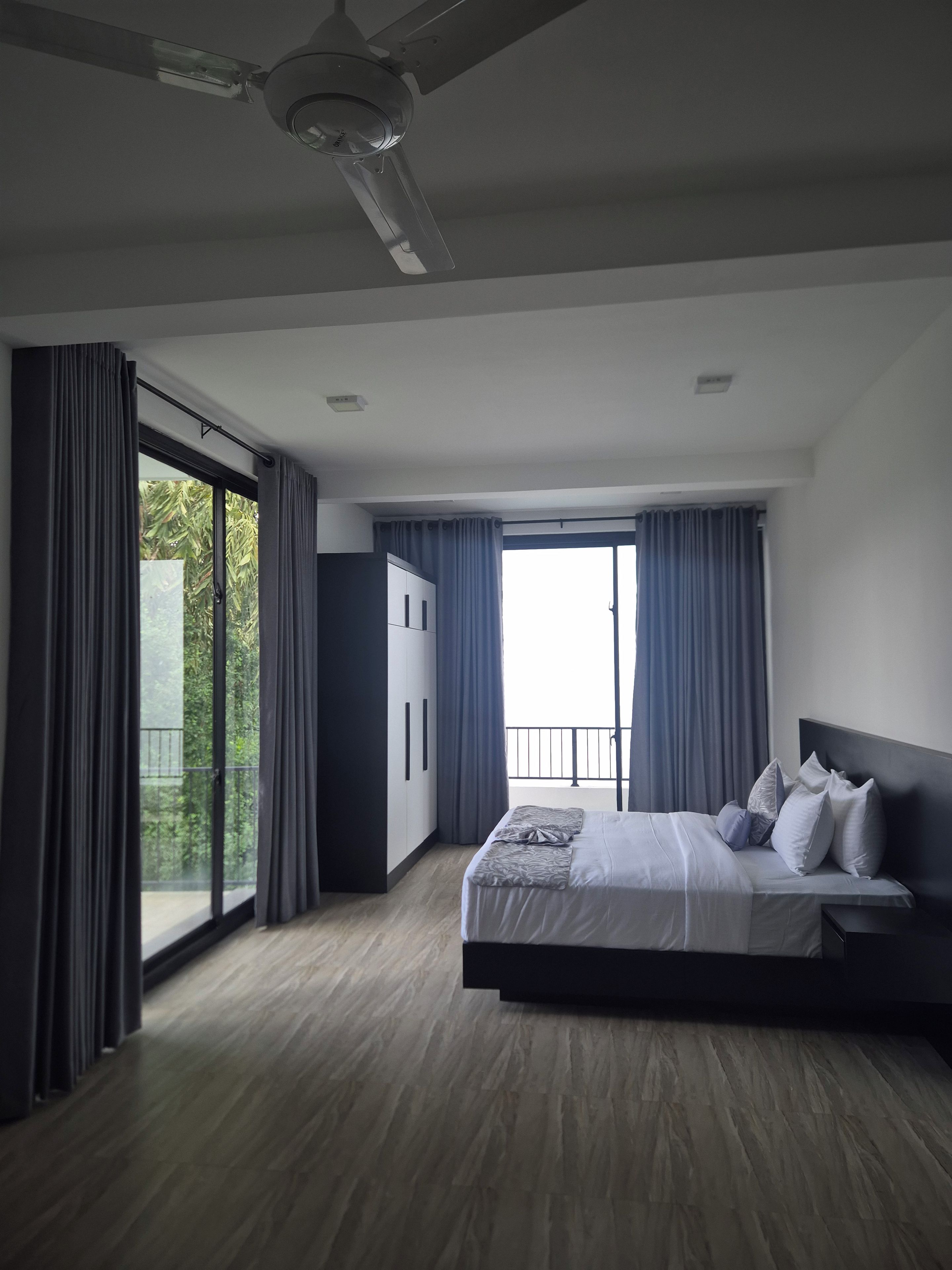 Een moderne slaapkamer met een groot bed, een kledingkast en een plafondventilator.