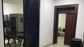 A modern interior with a sliding glass door leading to a kitchen area, a wooden door to another room, and a small outdoor area with a tree.