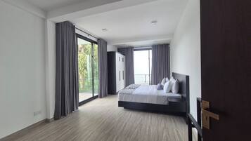A modern bedroom with a large bed, a wardrobe, and a balcony with curtains.