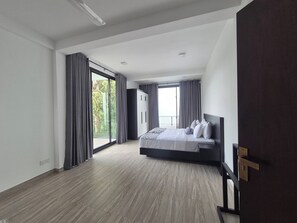Een moderne slaapkamer met een groot bed, een kledingkast en een balkon met gordijnen.