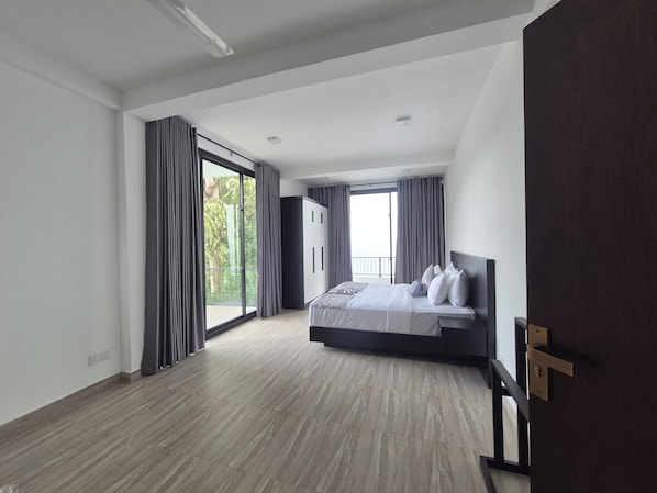 A modern bedroom with a large bed, a wardrobe, and a balcony with curtains.