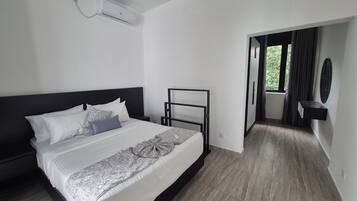 A modern hotel room with a large bed, a bedside table, a flat-screen TV, and a view of the outdoors.