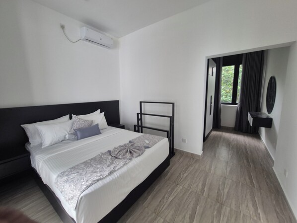 Een moderne hotelkamer met een groot bed, nachtkastje, flatscreen televisie en uitzicht op de omgeving.