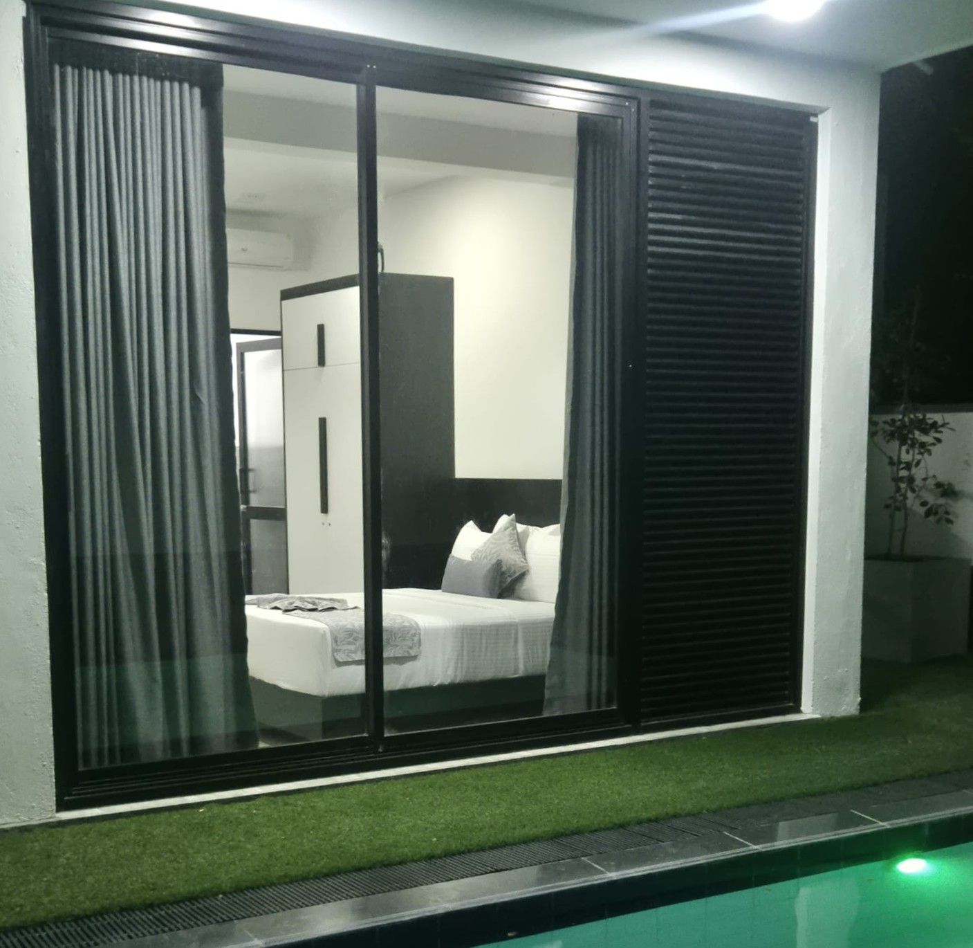 A bedroom with a bed, curtains, and a view of a room with a wardrobe.