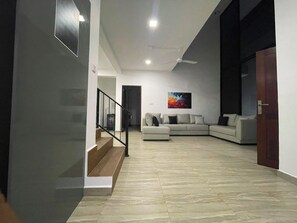 A modern living room with a sectional sofa, a staircase, and a ceiling fan.