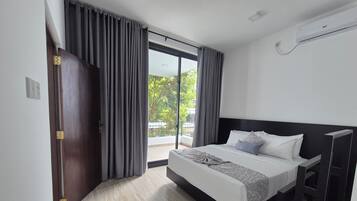 A modern hotel room with a large bed, a balcony, and a sliding door.