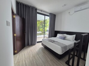 Een moderne hotelkamer met een groot bed, een balkon en een schuifdeur.