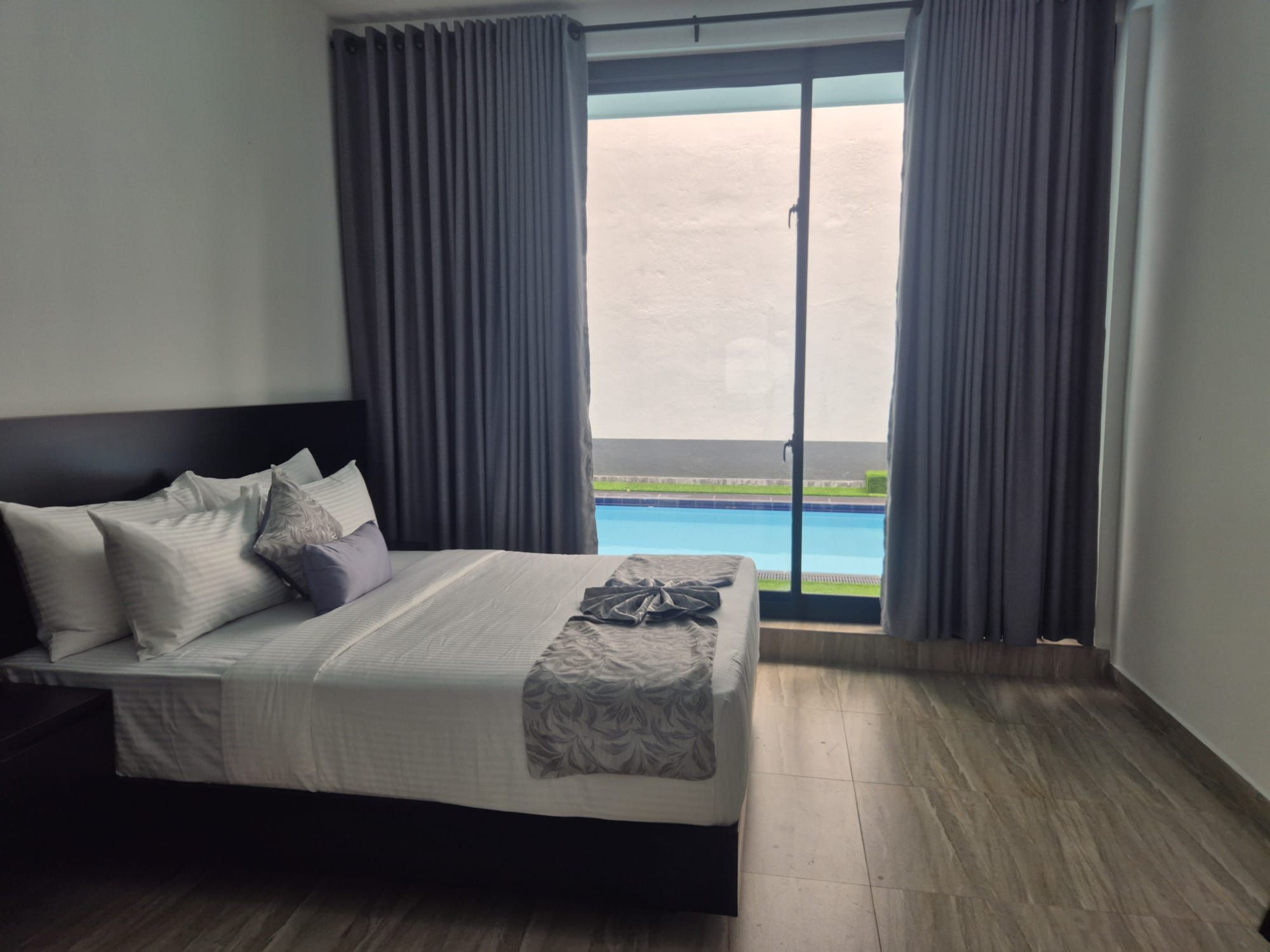 Een hotelkamer met een bed, zwembad uitzicht en een balkon.