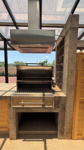Ein moderner Grill für den Außenbereich mit Edelstahlgehäuse, einem integrierten Backofen und einem Lüftungssystem.