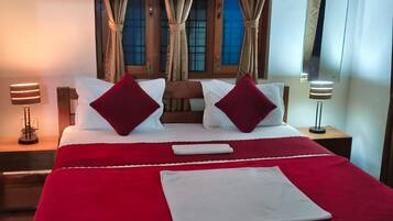 A neatly made bed with red and white bedding, a wooden headboard, and a window with curtains.