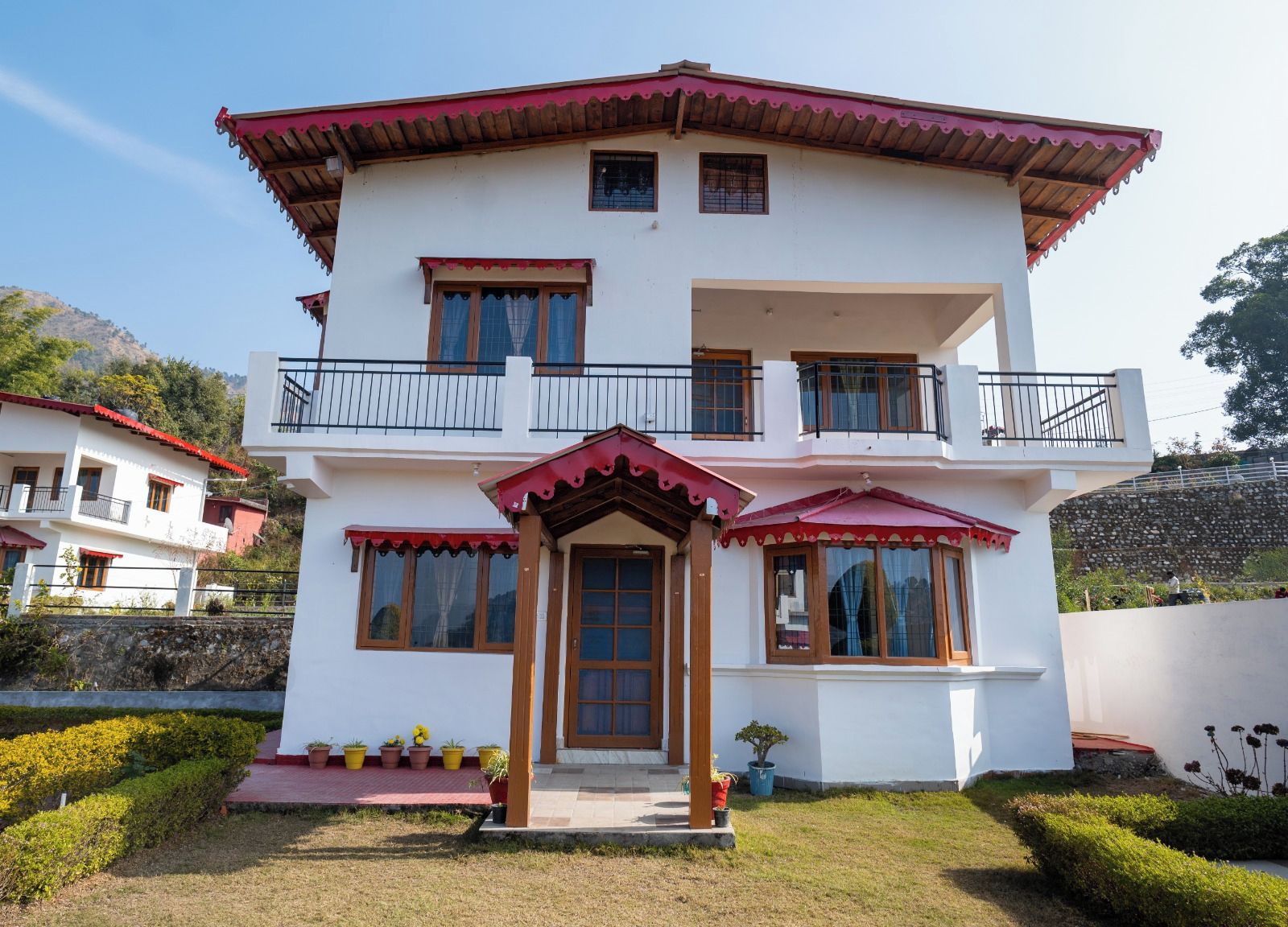 A two-story building with a balcony, a red roof, and a door with a wooden frame.