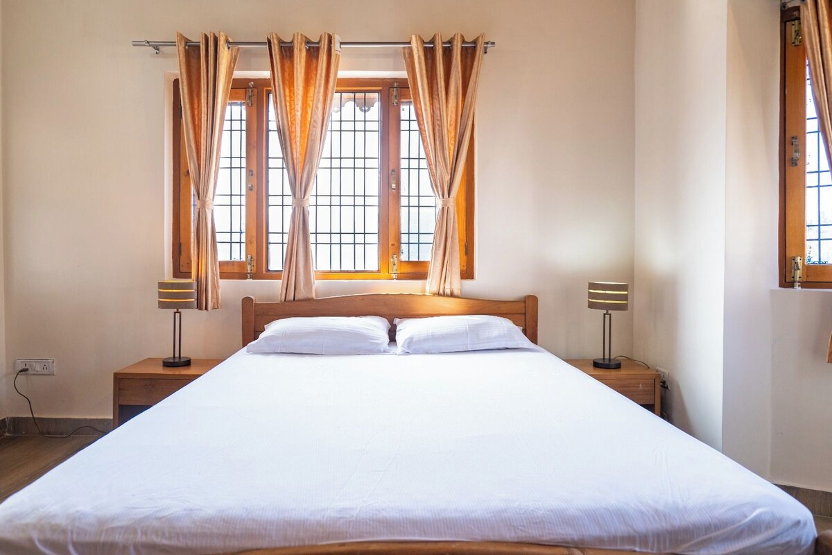 A hotel room with a large bed, two bedside tables, and curtains over windows.