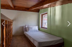 A small, single-bed room with a wooden ceiling and a window with bars. - Sundew N Lake Homestay (Nainital)