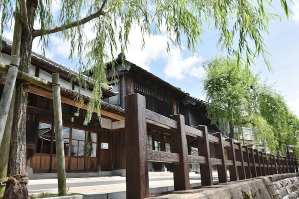 A traditional wooden building with a tiled roof, large windows, and a wooden fence.