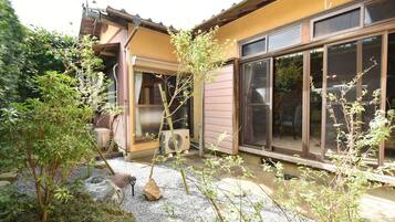 A residential building with a covered patio area, a large window, and a small air conditioning unit.