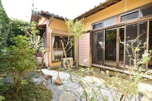 A residential building with a covered patio area, a large window, and a small air conditioning unit.
