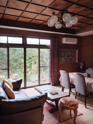 A room with a wooden ceiling, large windows, a sofa, a table, and a chair.