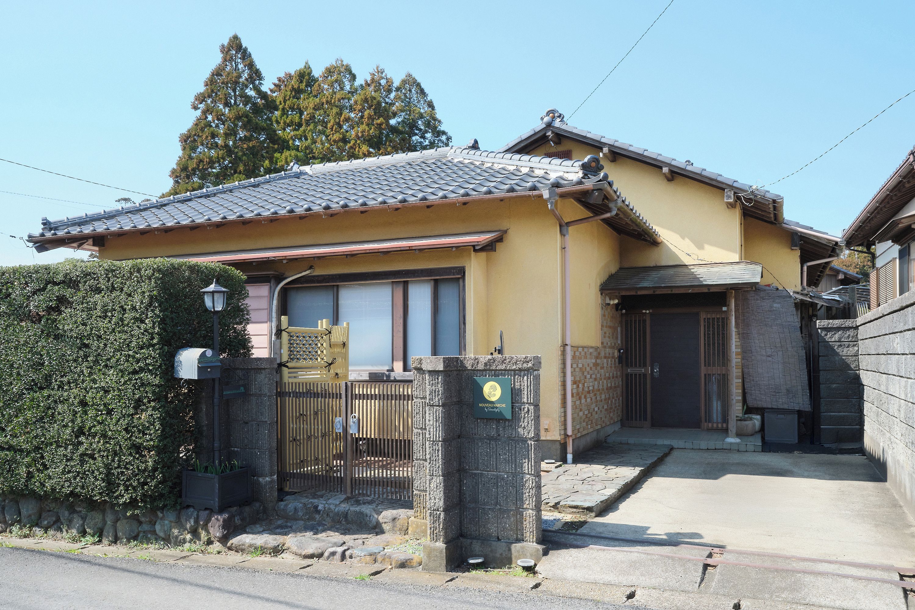 Una casa japonesa tradicional con techo de tejas, una puerta de madera y un muro de piedra.