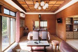 A dining area with a wooden ceiling, a table with chairs, a clock, and a television displaying 'NETFLIX'.