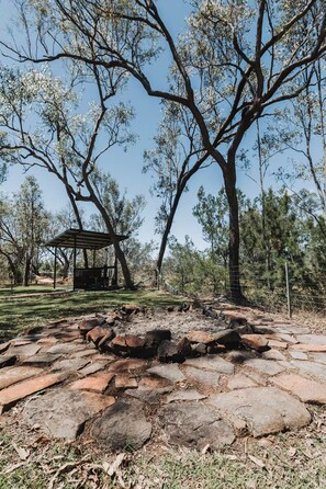 A stone-paved area with a gazebo and trees in the background. - The Riverstone | Luxury Bush Retreat (Millstream)