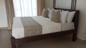 A bed with a wooden frame, white bedding, and a patterned throw.