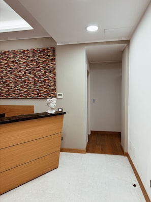 Un baño moderno con tocador de madera, pared con estampado geométrico e iluminación de techo.