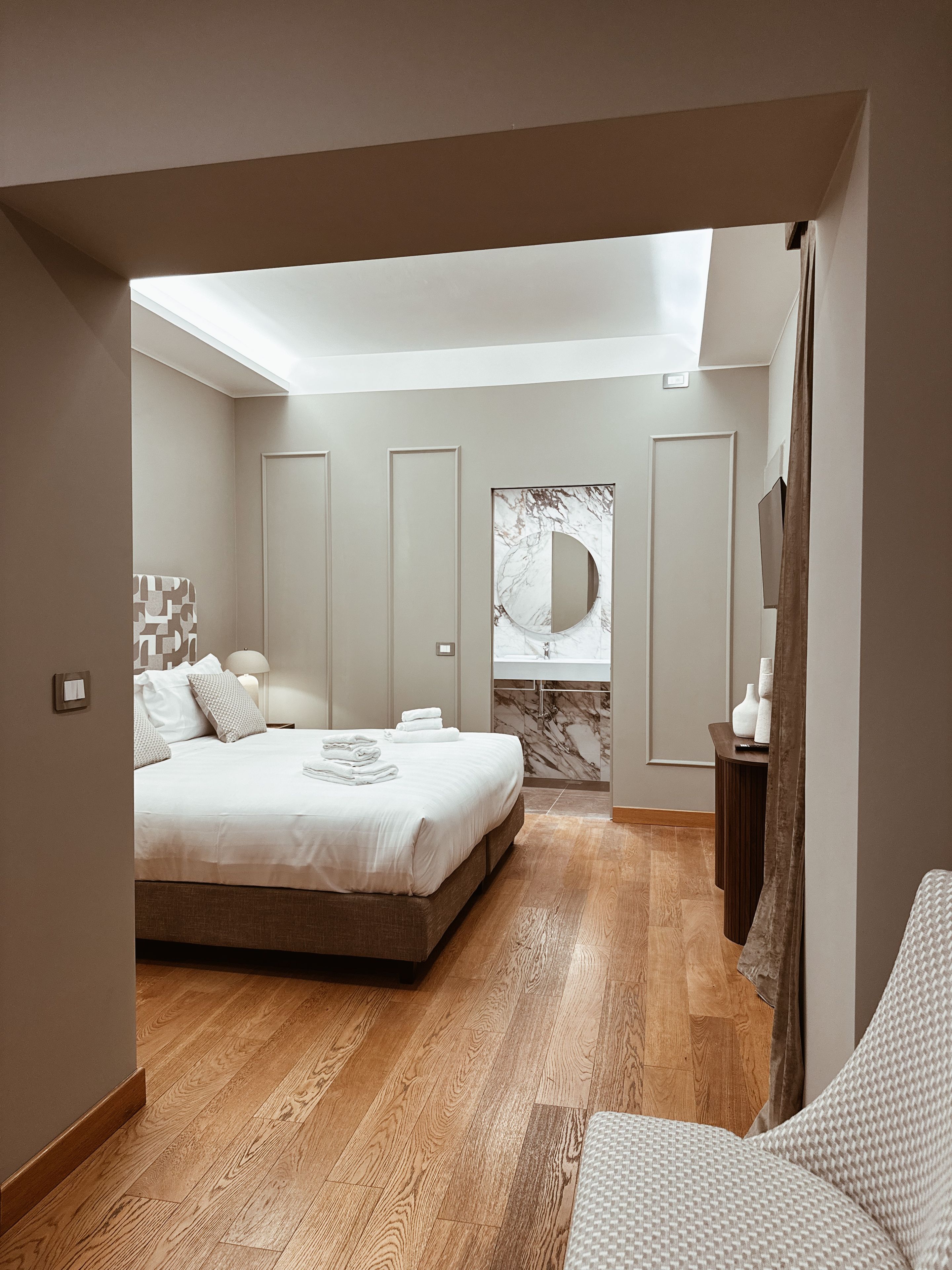 Un dormitorio moderno con una cama grande, un baño con lavamanos de mármol y un tragaluz.