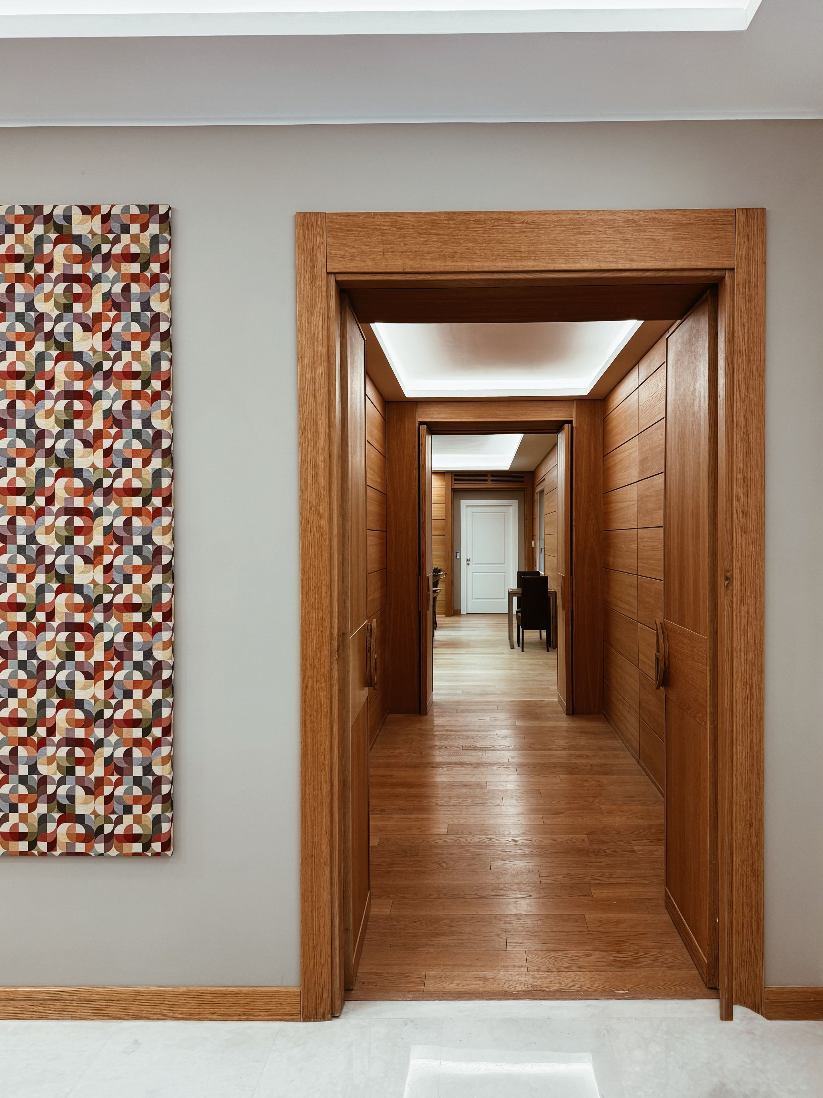 A hallway with wooden paneling and a geometric patterned wall.