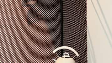 Una cocina compacta con una tetera sobre una encimera de madera, un tendedero encima y una pared con diseño.