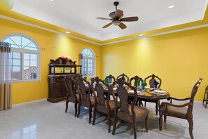 A dining room with a high ceiling fan, a large window, and a dining table set for six. - Hospitality Expert VSV TF 3BR Chef Pool  (Montego Bay)