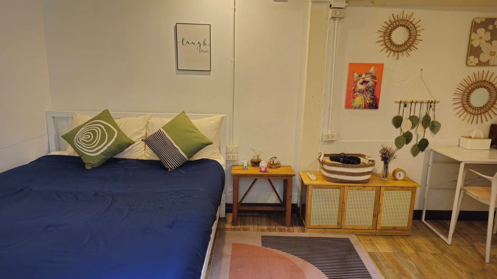 A bedroom with a bed, bedside table, and a small desk with a basket.
