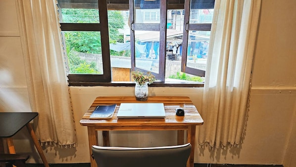 A small wooden desk with a laptop, a smartphone, and a vase with a plant. - Charming Home Chiang Mai (Chiang Mai)
